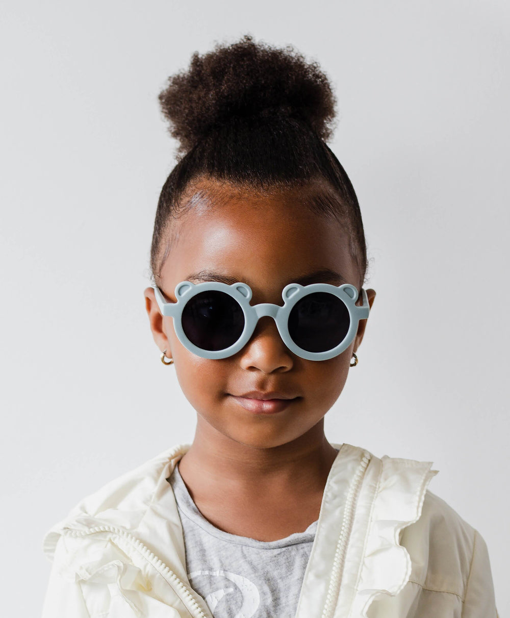 Little girl with blue teddy bear sunglasses for kids, in the style LITLLE LUSSO TEDDY.
